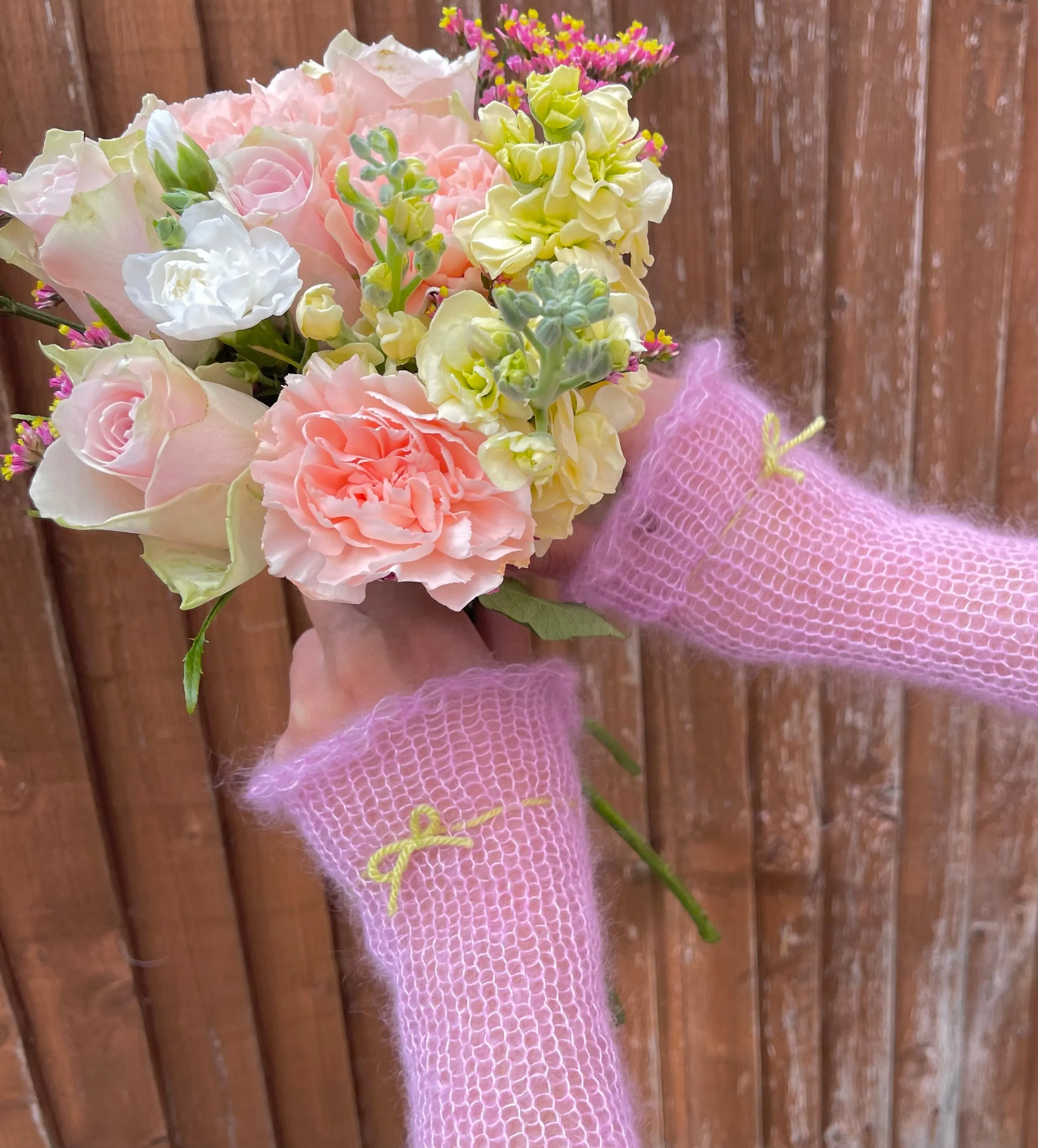 Handmade knitted mohair hand warmers in baby pink with lime green bow