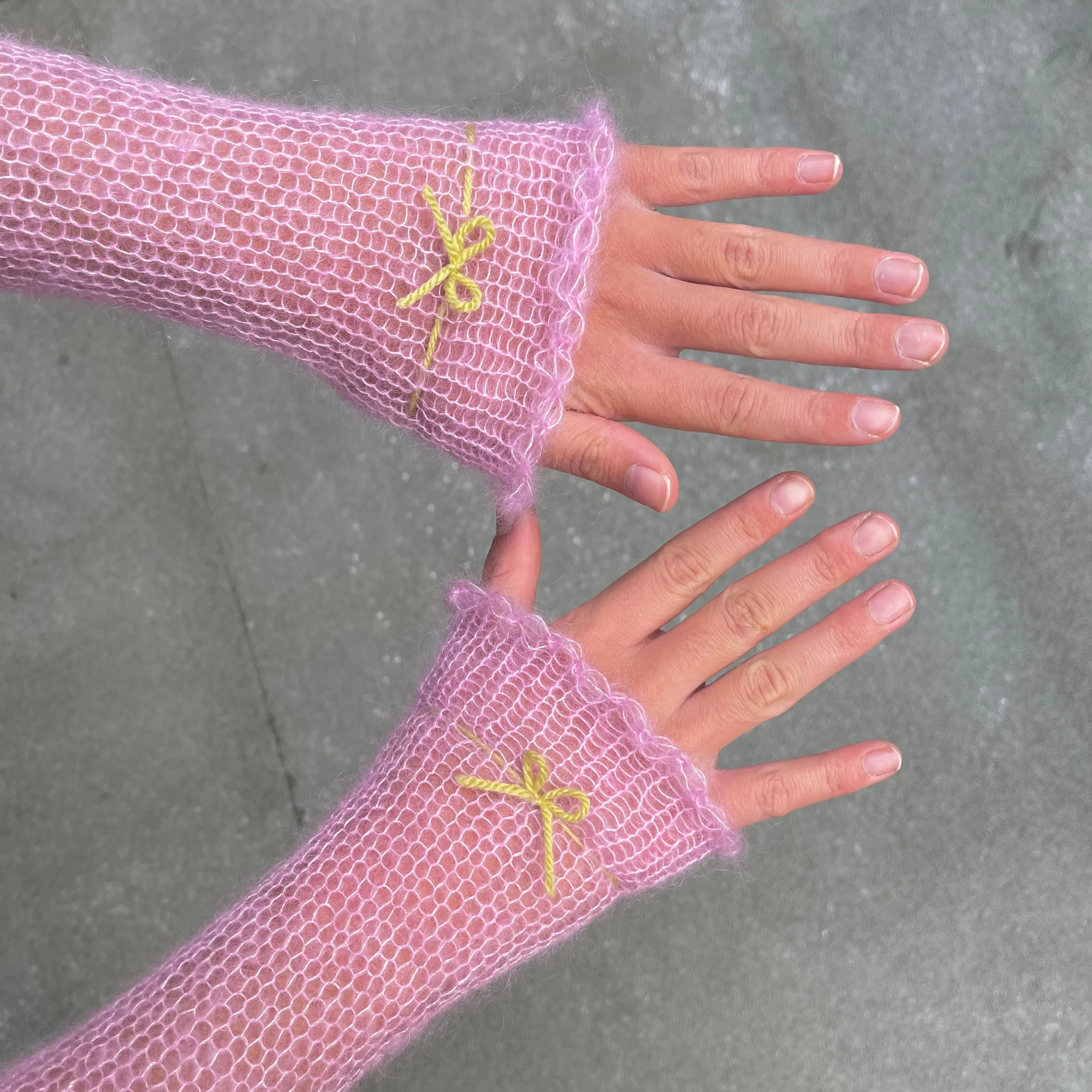 Handmade knitted mohair hand warmers in baby pink with lime green bow